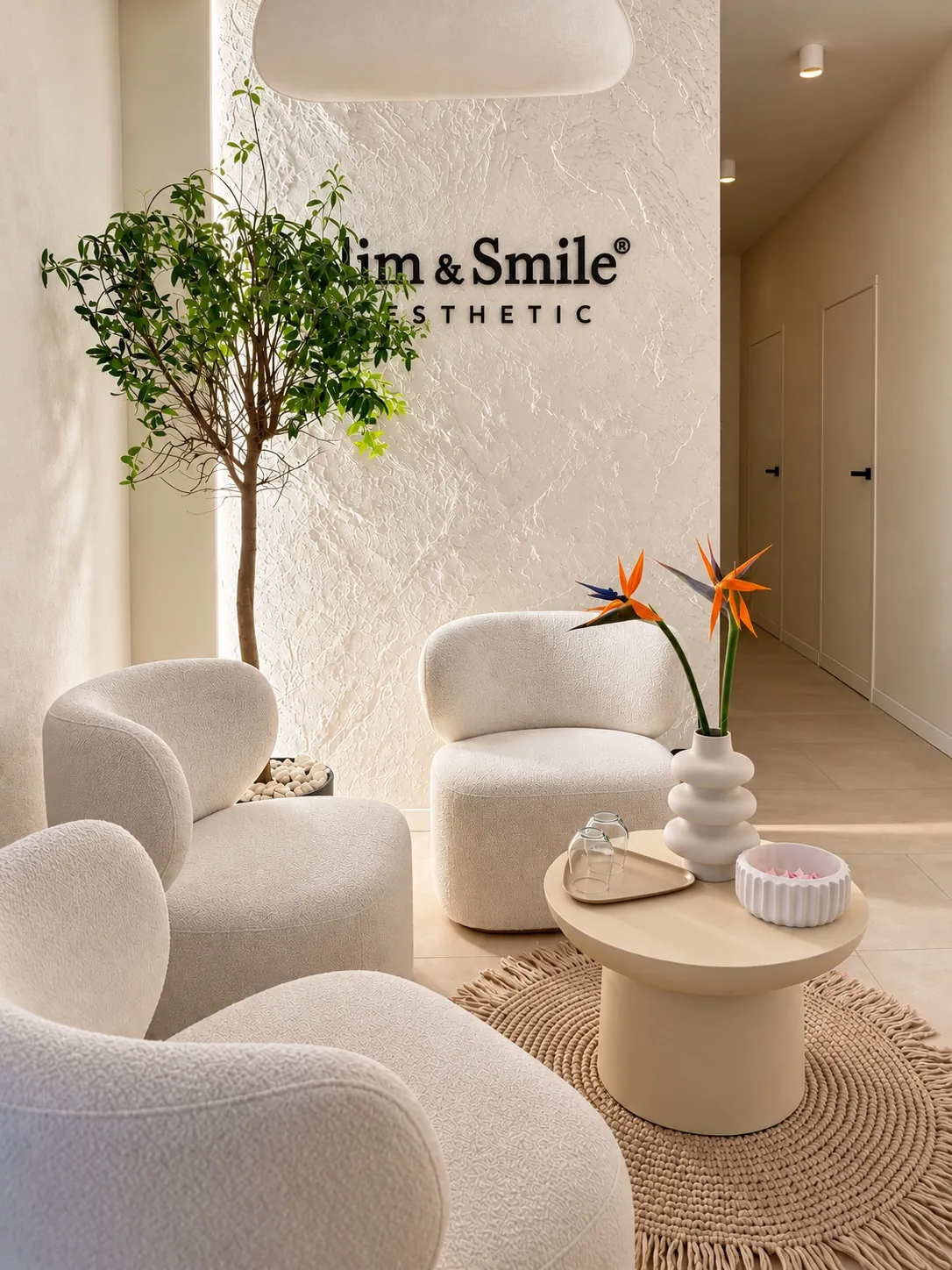 Wnętrze salonu Slim & Smile w Gorzowie Wielkopolskim, jasne fotele, rośliny i logo na fakturowanej ścianie